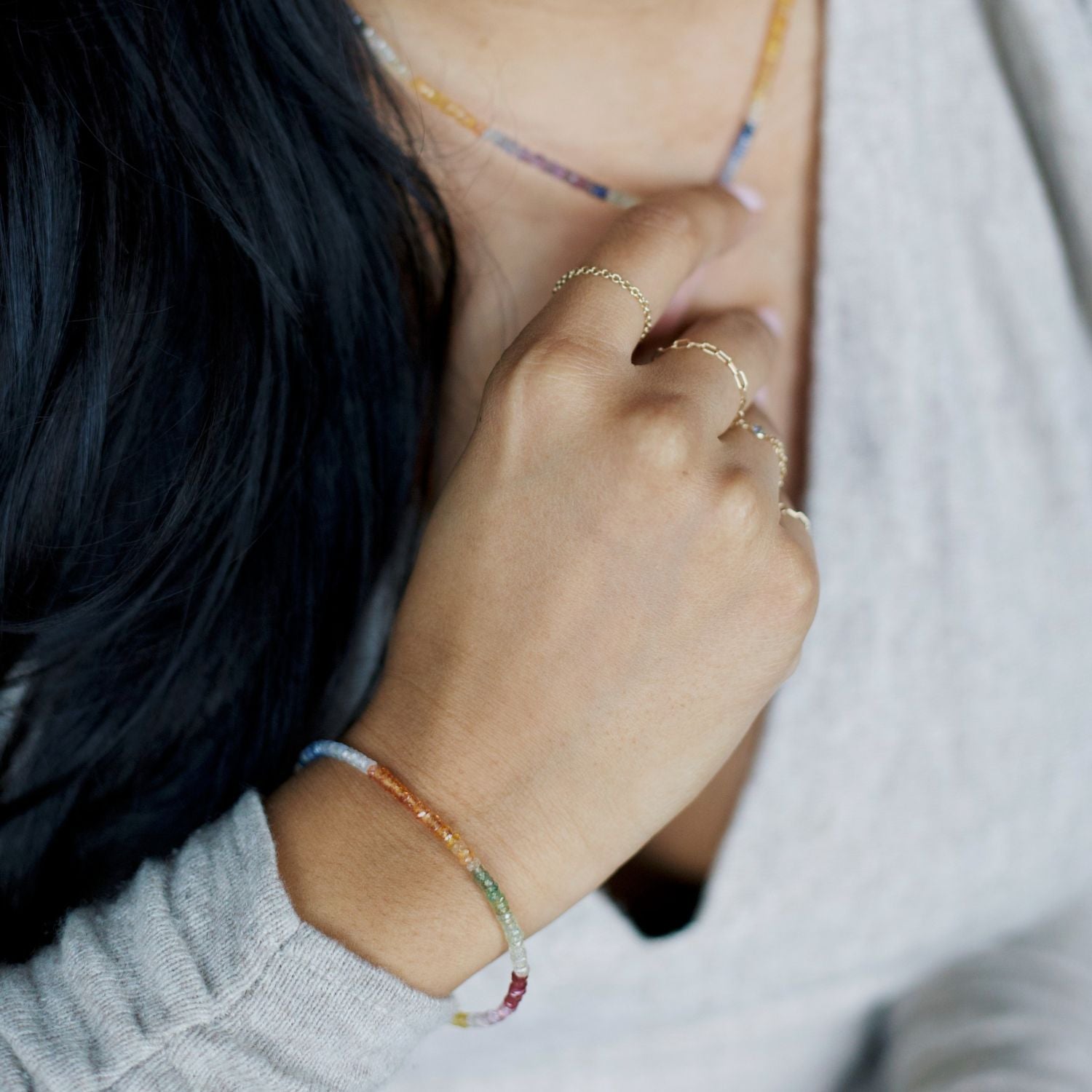 Close-up of a woman wearing a rainbow sapphire bracelet on her wrist.