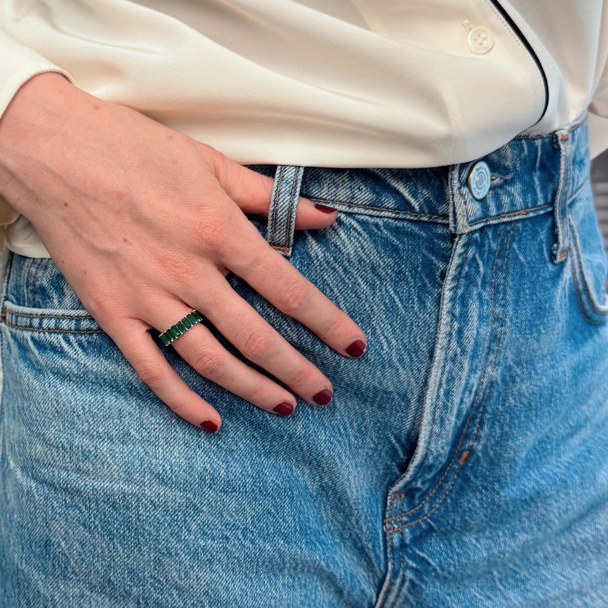 woman in blue jeans wearing an emerald wedding ring