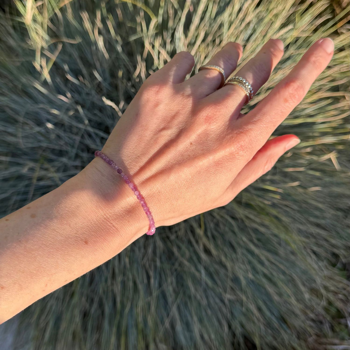 woman wearing a pink ruby bracelet against a natural background