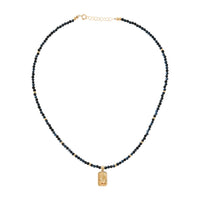 Necklace with blue sapphire beads and a gold celestial pendant on a white background