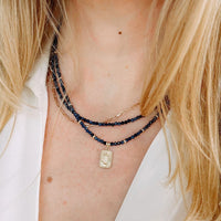 Close-up of a person wearing multiple blue sapphire necklaces with a focus on the neck and shoulders.