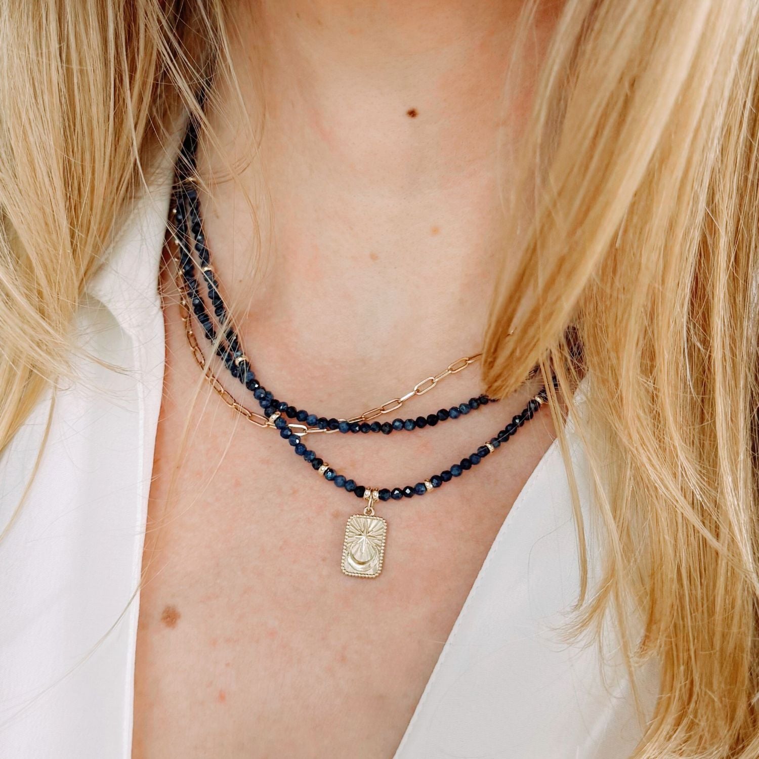 Close-up of a person wearing multiple blue sapphire necklaces with a focus on the neck and shoulders.