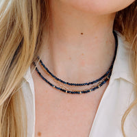 Close-up of a person wearing a stack of necklaces with a neutral background
