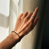 Hand with multiple rings and a bracelet against a neutral background