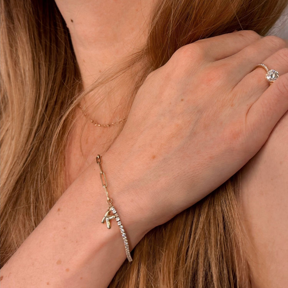 woman wearing a 14k gold and diamond bracelet with K letter charm