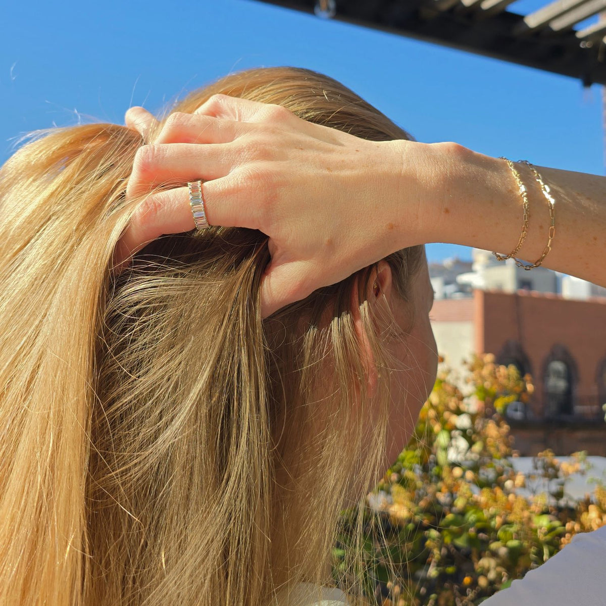 woman wearing a baguette diamond eternity ring running her hand through her blonde hair