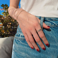 woman wearing a baguette eternity diamond ring with her hand in her jeans and red nail polish