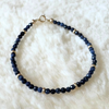 Navy blue sapphire beaded bracelet with gold accents on a white fluffy surface