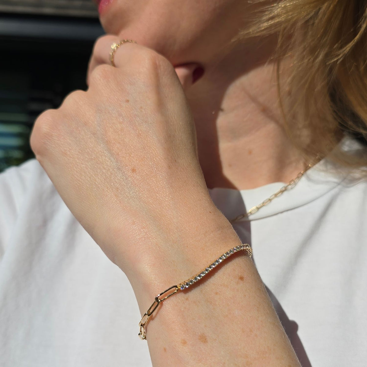 woman's wrist wearing a diamond and gold chain bracelet