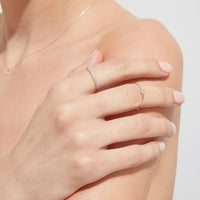 Close-up of a hand wearing two diamond rings on a light background