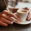 woman wearing gold rings drinking espresso in paris cafe