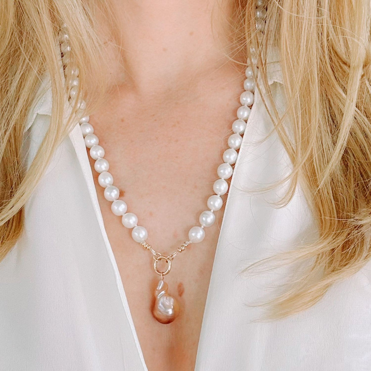Freshwater Pearl necklace with a single baroque pearl pendant worn by a person with blonde hair.