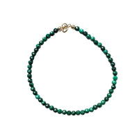 Malachite beaded bracelet with a 14k gold clasp on a white background