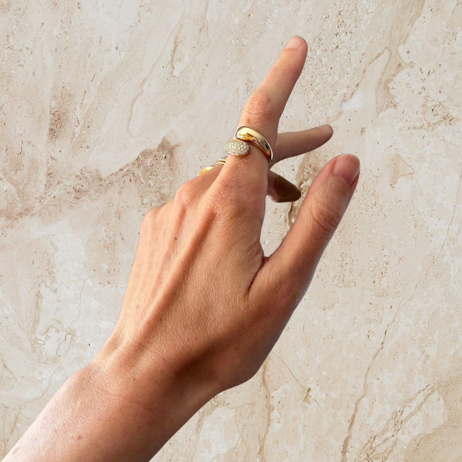 Hand with gold diamond ring on a marble background