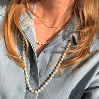Person wearing a 30 inch freshwater pearl necklace with a denim shirt