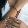 Close-up of a woman's wrist wearing a blue sapphire beaded bracelet with neutral clothing.