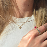 woman in a white tee wearing a gold chain necklace with a letter K charm