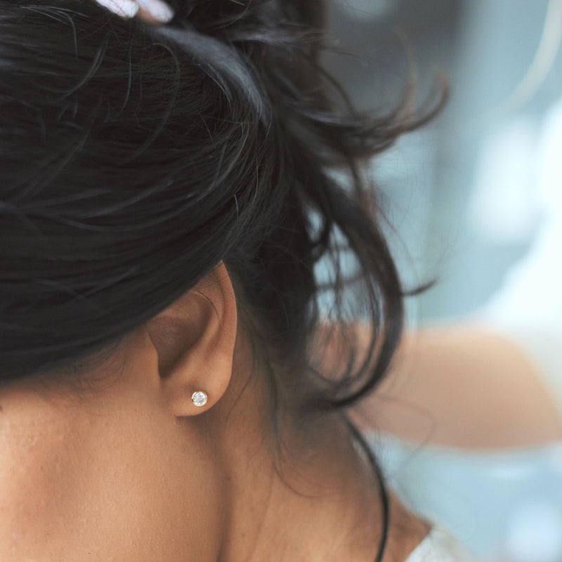 Close-up of an ear with a diamond earring against a blurred background