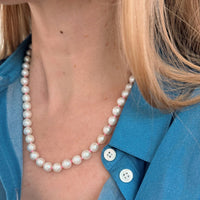 Pearl necklace worn by a person with a blue shirt