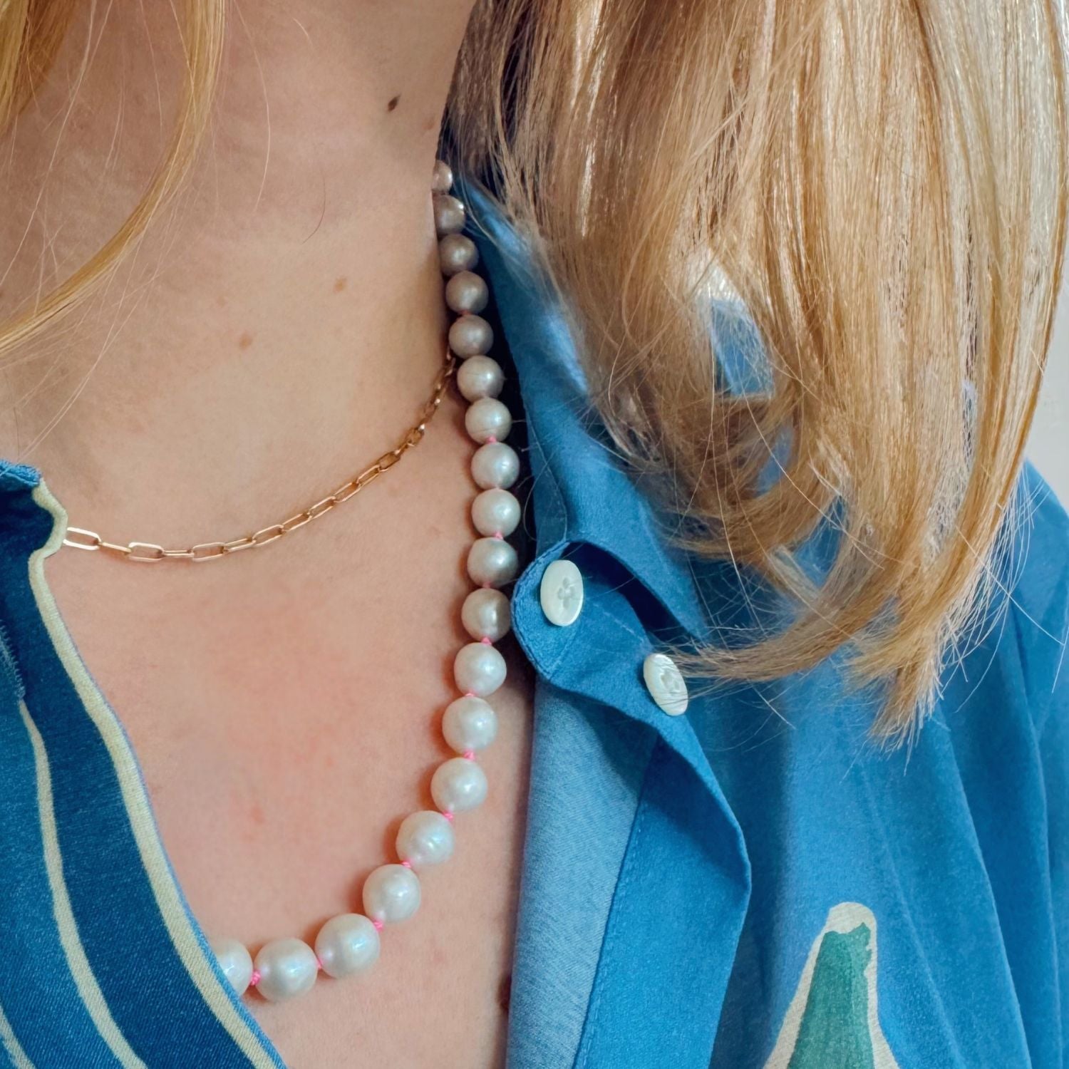 Person wearing a pearl necklace with a blue shirt