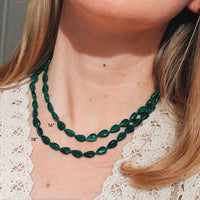 Green necklace on a person with measurements indicated