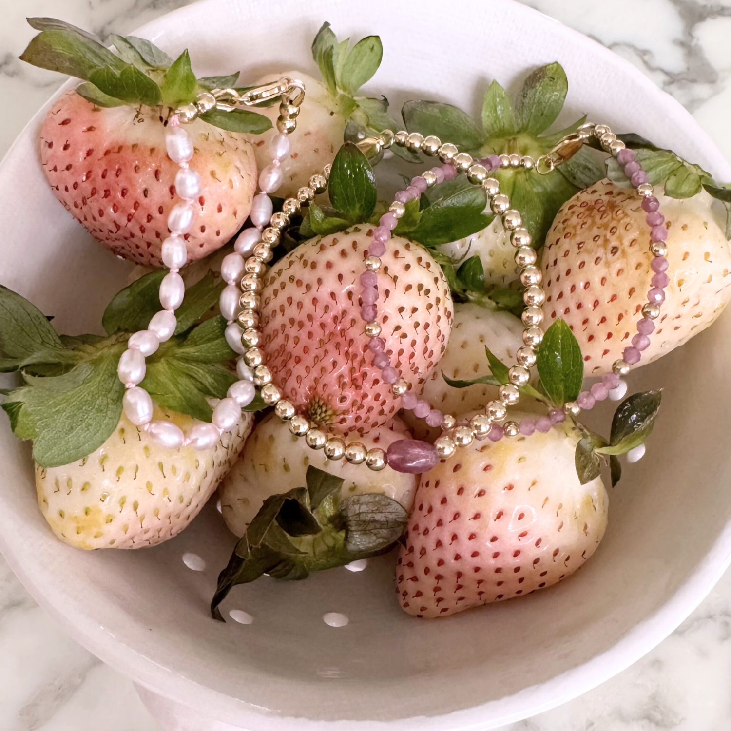 Strawberries with beaded pink bracelets on a white plate