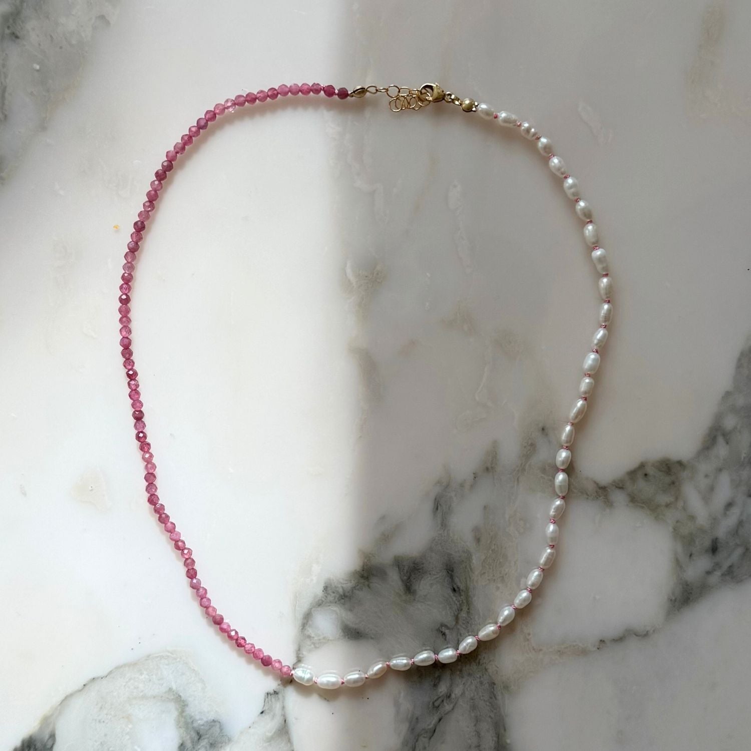 Necklace with pink beads and white pearls on a marble surface