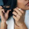 Close-up of a person wearing a diamond heart-shaped ring and 14k gold ring.