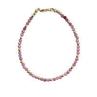 Bracelet with pink beads and gold accents on a white background