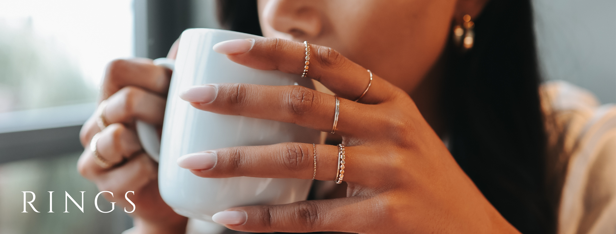 Gold rings shown on woman drinking coffee