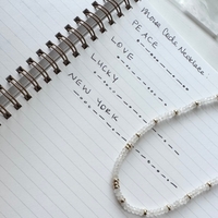 Morse Code Message Necklace with moonstone beads on a notebook page with love