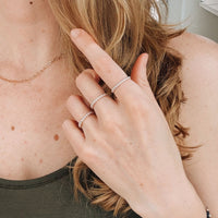 Close-up of a person wearing multiple silver rings on their hand.
