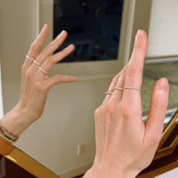 Close-up of hand wearing silver rings with a blurred mirror background