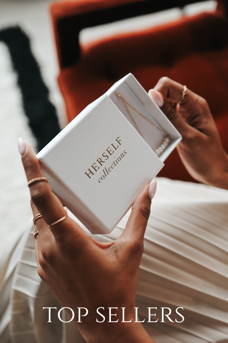 Person holding a jewelry box labeled 'Herself Collections' with 'Top Sellers' text.