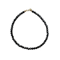 Black beaded bracelet with a 14k gold clasp on a white background