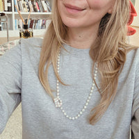 Woman wearing a pearl necklace in a casual indoor setting