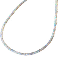 A beaded opal necklace made of small, round, iridescent opal-like beads arranged in a curved U-shape against a plain white background.